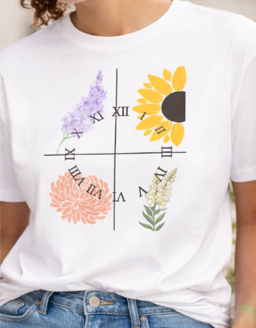 White t-shirt with floral and Roman numeral design worn by a person.