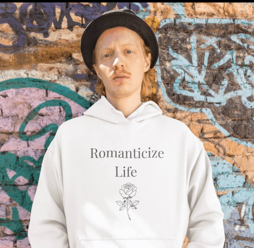 Person wearing a white hoodie with text, standing in front of a colorful mural.