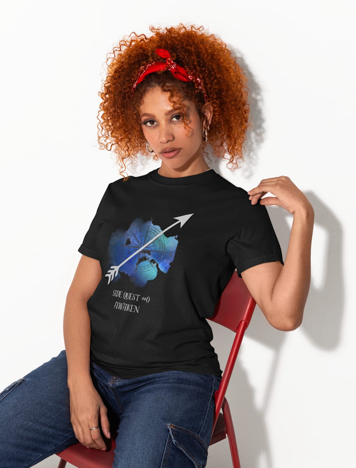 Woman wearing a black t-shirt with a graphic design, sitting on a red chair against a white background.